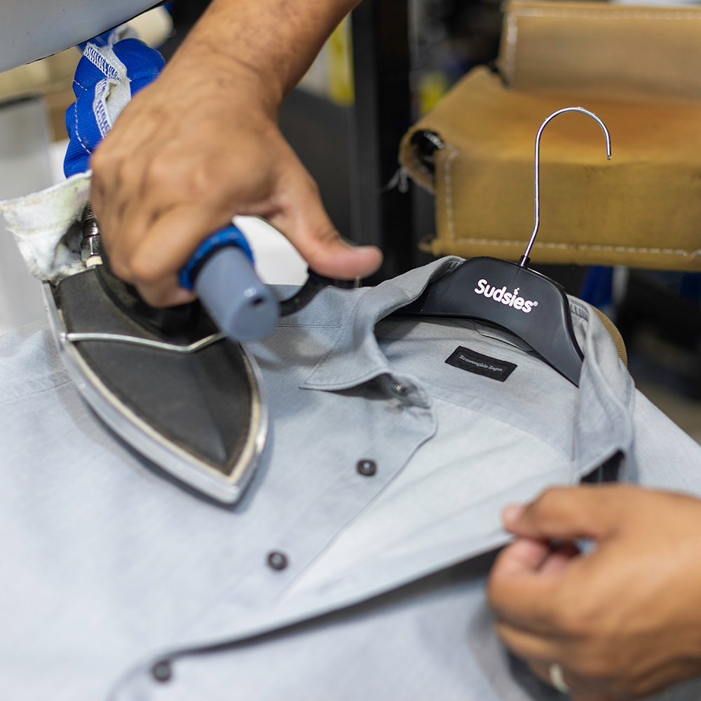 Sudsies expert pressing a luxury dress shirt during couture garment care in Miami